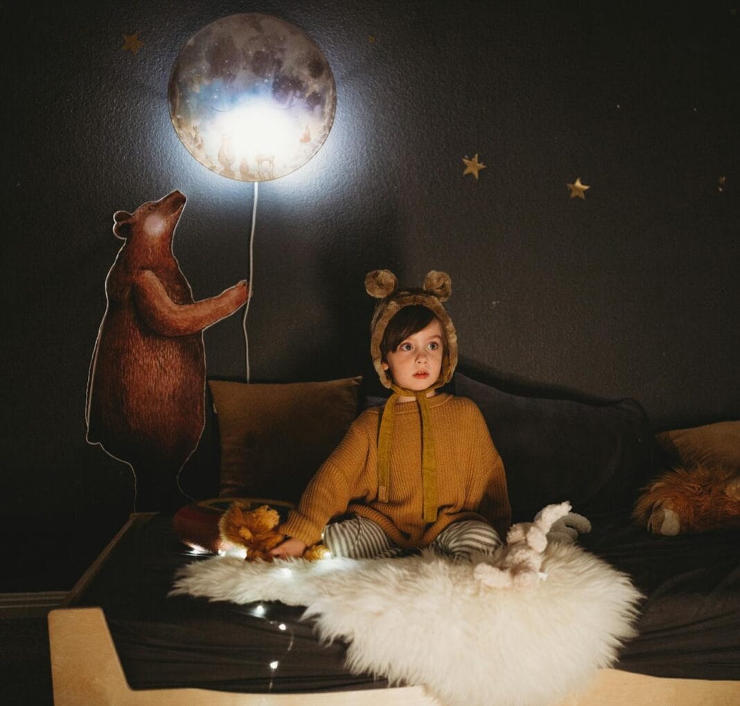 Dziecko w leśnym pokoju z misiami i świecącą lampką księżyca