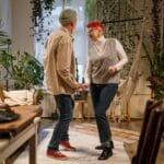 Uśmiechnięte starsze małżeństwo tańczy w salonie pełnym roślin